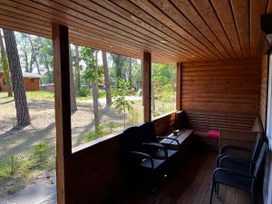 een afgeschermde veranda met stoelen, een tafel en ramen bij Domek Dębowy 2 in Lubniewice