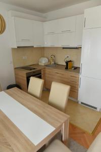 a kitchen with white cabinets and a table and chairs at Dobi Apartmani WING in Jagodina