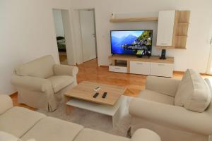 a living room with white furniture and a flat screen tv at Dobi Apartmani WING in Jagodina