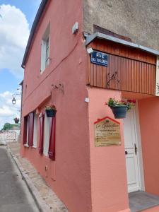 un edificio rojo con macetas de flores en el costado en La graineterie89 en Pont-sur-Yonne