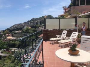 una donna in piedi sul balcone di un palazzo con sedie di Mare Luna Casa a Taormina