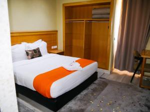 una camera da letto con un grande letto con una coperta arancione di Hotel Golden Flora a Beni Mellal