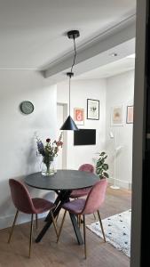 bedandbreakfastrouveen في Rouveen: غرفة طعام مع طاولة سوداء وكراسي وردية