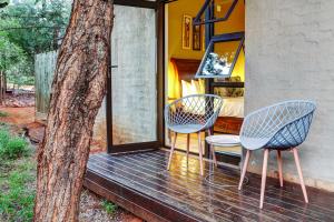 two chairs and a table on a deck next to a tree at Wildheart Safari - MAIN in Hoedspruit