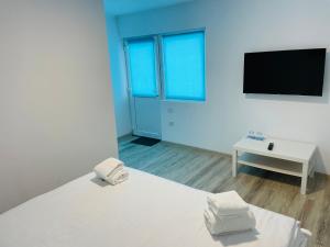 um quarto branco com uma cama e uma televisão em Blue Sky Transalpina em Săsciori