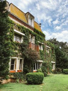 un edificio cubierto de hiedra con ventanas y un patio en Estancia Villa Maria en Ezeiza