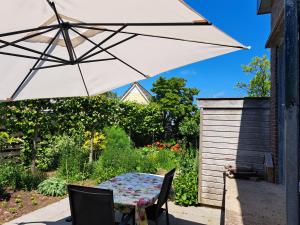 een tafel en stoelen met een parasol op een patio bij luxe ruime studio op unieke, rustige locatie in Dokkum