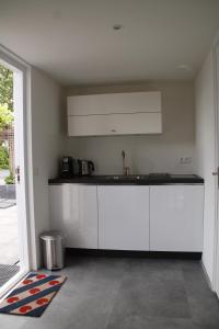 una cocina con armarios blancos y fregadero en luxe ruime studio op unieke, rustige locatie, en Dokkum