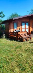 a log cabin with a porch and a grill at Domek letniskowy u Bodzia in Kruklanki