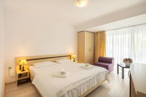 a hotel room with a bed and a purple chair at Hotel Venus in Mamaia