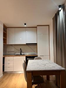 a kitchen with a table and chairs and white cabinets at Apartman Kosuta Lux in Tjentište