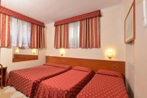 a hotel room with two beds and two windows at Hotel Chicago in Rome