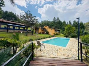 a swimming pool in a yard next to a house at Sitio Oliveira Ibiuna in Ibiúna