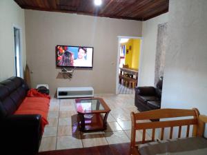 a living room with a couch and a tv on the wall at Sitio Oliveira Ibiuna in Ibiúna