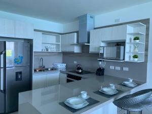 a kitchen with white cabinets and a counter with dishes on it at Grand Diamond Beach, Dep 2 dormitorios in Tonsupa
