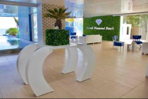 a white bench in a lobby with a palm tree at Grand Diamond Beach, Dep 2 dormitorios in Tonsupa