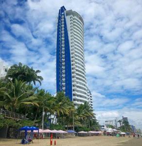 a tall blue building on a beach with palm trees at Grand Diamond Beach, Dep 2 dormitorios in Tonsupa