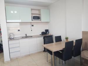 a kitchen with white cabinets and a wooden table and chairs at Monoambiente CENTRICO Neuquén Capital - ESPECTACULAR VISTA in Neuquén