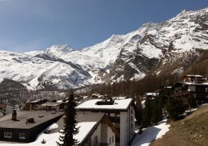 a village with snow covered mountains in the background at Victoria's Home - luxurious penthouse in Saas-Fee