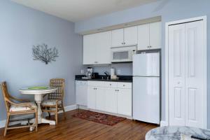 a kitchen with white cabinets and a white refrigerator at Harbour House at the Inn 207 in Fort Myers Beach