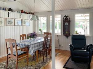 une salle à manger avec une table, des chaises et une horloge dans l'établissement Holiday home Torhamn II, à Torhamn