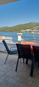 a patio with two chairs and a view of the water at Apartments Vuko Seget Vranjica in Seget Vranjica