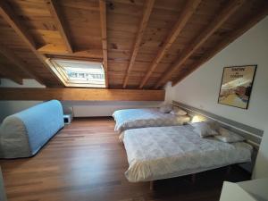 two beds in a room with a wooden ceiling at Bonito dúplex con vistas al mar in Comillas