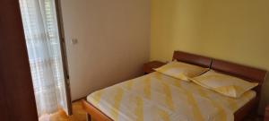 a bedroom with a bed with two pillows and a window at Apartments Vuko Seget Vranjica in Seget Vranjica