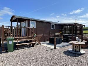 a wooden cabin with a bench and a table at AC/DC Glamping in New Aberdour