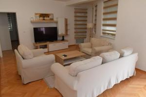 uma sala de estar com mobiliário branco e uma televisão de ecrã plano em Dobi Apartmani WING 7 em Jagodina
