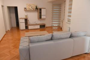 um sofá branco numa sala de estar com pisos em madeira em Dobi Apartmani WING 7 em Jagodina
