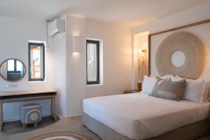 a bedroom with a large white bed and a mirror at Kosmitis Suites & Villas in Naousa