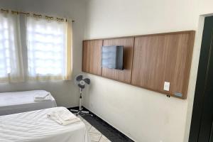 a room with two beds and a flat screen tv at Hotel Turi in Barra Bonita