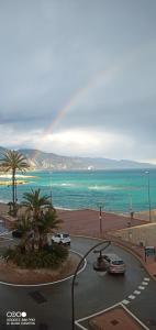 un arco iris sobre el océano con coches estacionados en una calle en Appartement avec jardin en Roquebrune-Cap-Martin