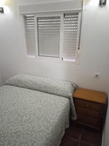 1 dormitorio con cama y mesa de madera en La casita de Ahinoan. en Barbate