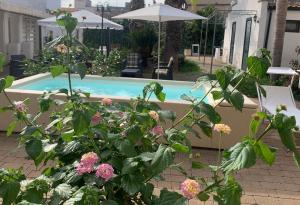 a bush with flowers in front of a swimming pool at CORTE CARAFA "un'Oasi nel Centro Storico con parcheggio interno riservato" in Nardò