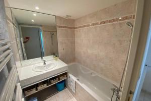 a bathroom with a sink and a tub and a mirror at Bright 56m near Pornichet's hypercentre in Pornichet