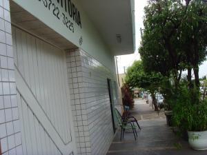 a white building with tables and chairs on a sidewalk at Hotel Vitoria Andradina in Andradina