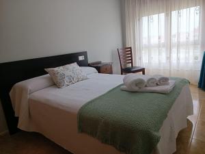 Apartamento Isla de Arousa - Riasón في إيسلا دي أروسا: غرفة نوم عليها سرير وفوط