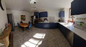 a kitchen with blue cabinets and a table and chairs at 2 CHAMBRES DANS MAISON EN PIERRE ATYPIQUe in Lœuilley