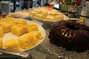 a table with two plates of cakes and a chocolate cake at Hotel Aliança Express in Rio do Sul