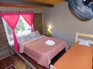 a bedroom with a pink bed and a window at Un lugar en el mundo in Mina Clavero
