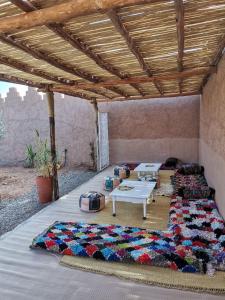 un patio cubierto con mesa y almohadas en el suelo en Ksar Montana Gîtes, Chambres piscine, en Taforhalt