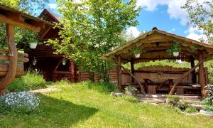 a wooden pavilion in front of a log cabin at У Медовому Раю in Rostoka