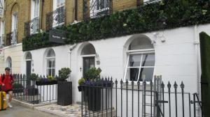 una mujer parada frente a una casa blanca en Alhambra Hotel, en Londres