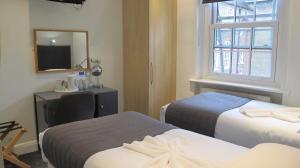 a hotel room with two beds and a mirror at Alhambra Hotel in London