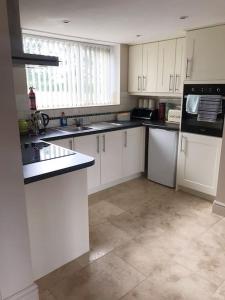 a kitchen with white cabinets and black appliances at Kenns Farm - 2 Beautiful Barns in Carterton