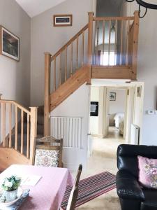 ein Wohnzimmer mit einem Tisch und einer Treppe in der Unterkunft Kenns Farm - 2 Beautiful Barns in Carterton