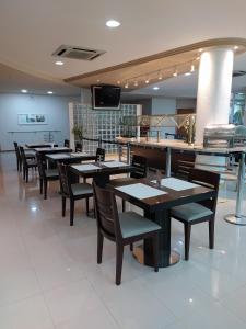 a restaurant with tables and chairs and a counter at Hotel Aliança Express in Rio do Sul