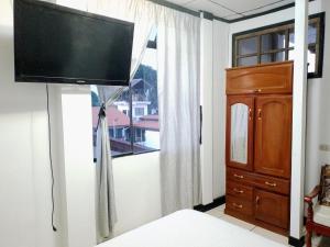 HABITACIÓN AMUEBLADA Y ACOGEDORA في Puerto Callao: غرفة نوم مع تلفزيون بشاشة مسطحة على جدار